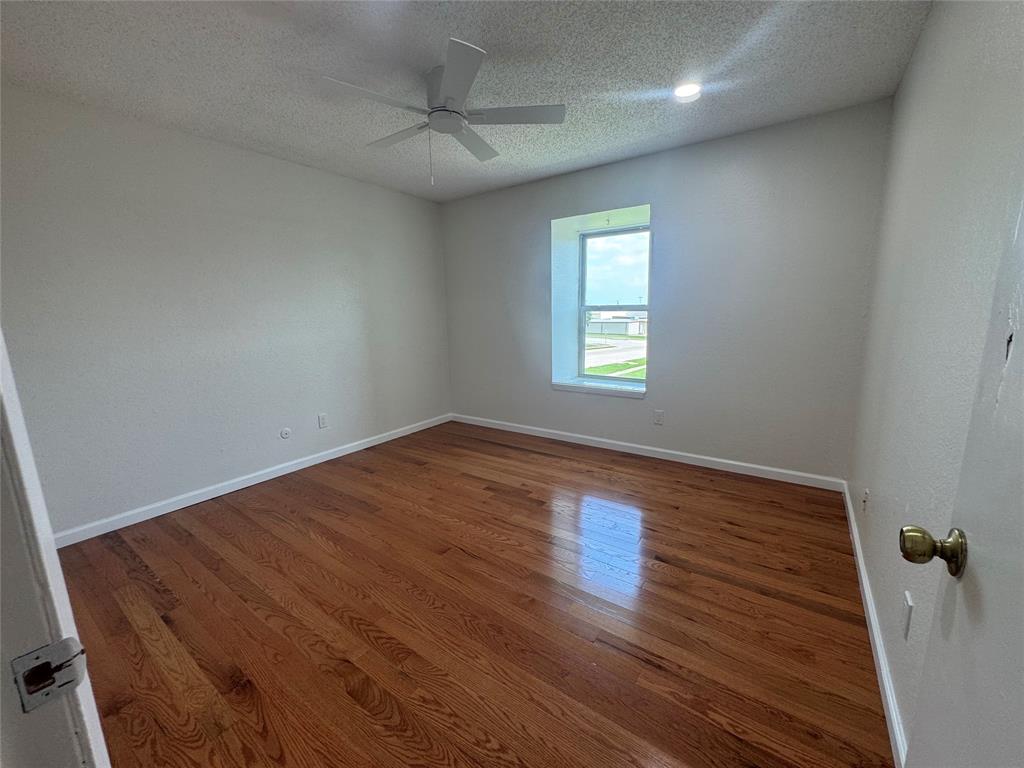 9519 Westpark Drive Benbrook, TX 76126 - Photo 6 of 9 a view of an empty room with wooden floor and a window