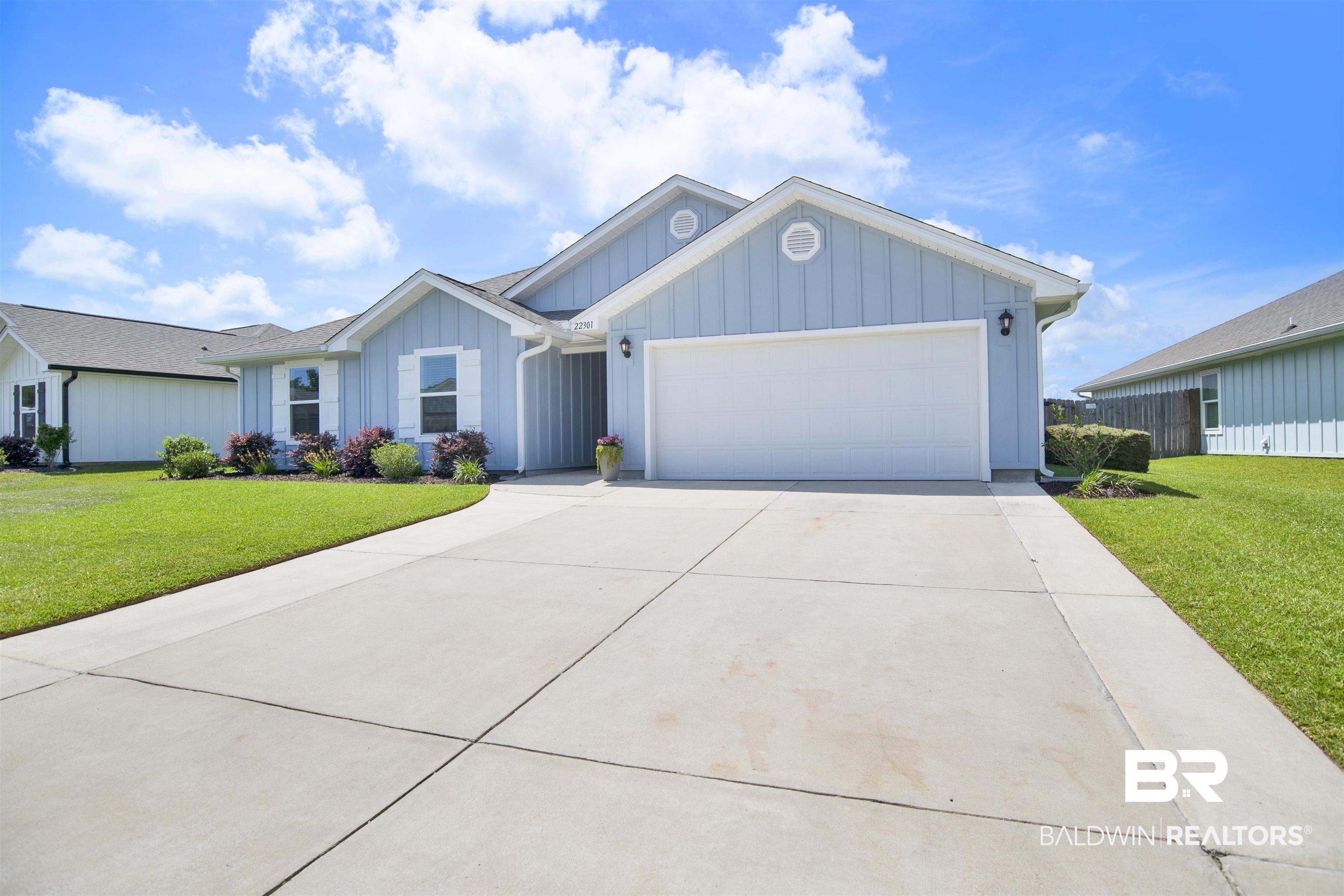 22301 Early Dawn Circle Foley, AL 36535 - Photo 45 of 45 Light blue board-and-batten siding with white trim, a two-car garage, and a concrete driveway