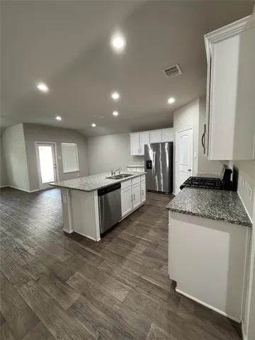 a large kitchen with stainless steel appliances granite countertop a large counter top and a wooden floors