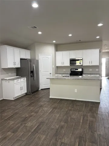 a large kitchen with stainless steel appliances a large counter top a stove and a sink