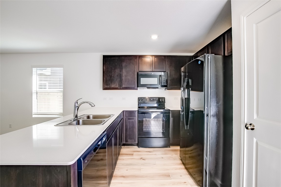 1133 Largemouth Road Bastrop, TX 78602 - Photo 7 of 16 a kitchen with stainless steel appliances granite countertop a sink refrigerator and microwave