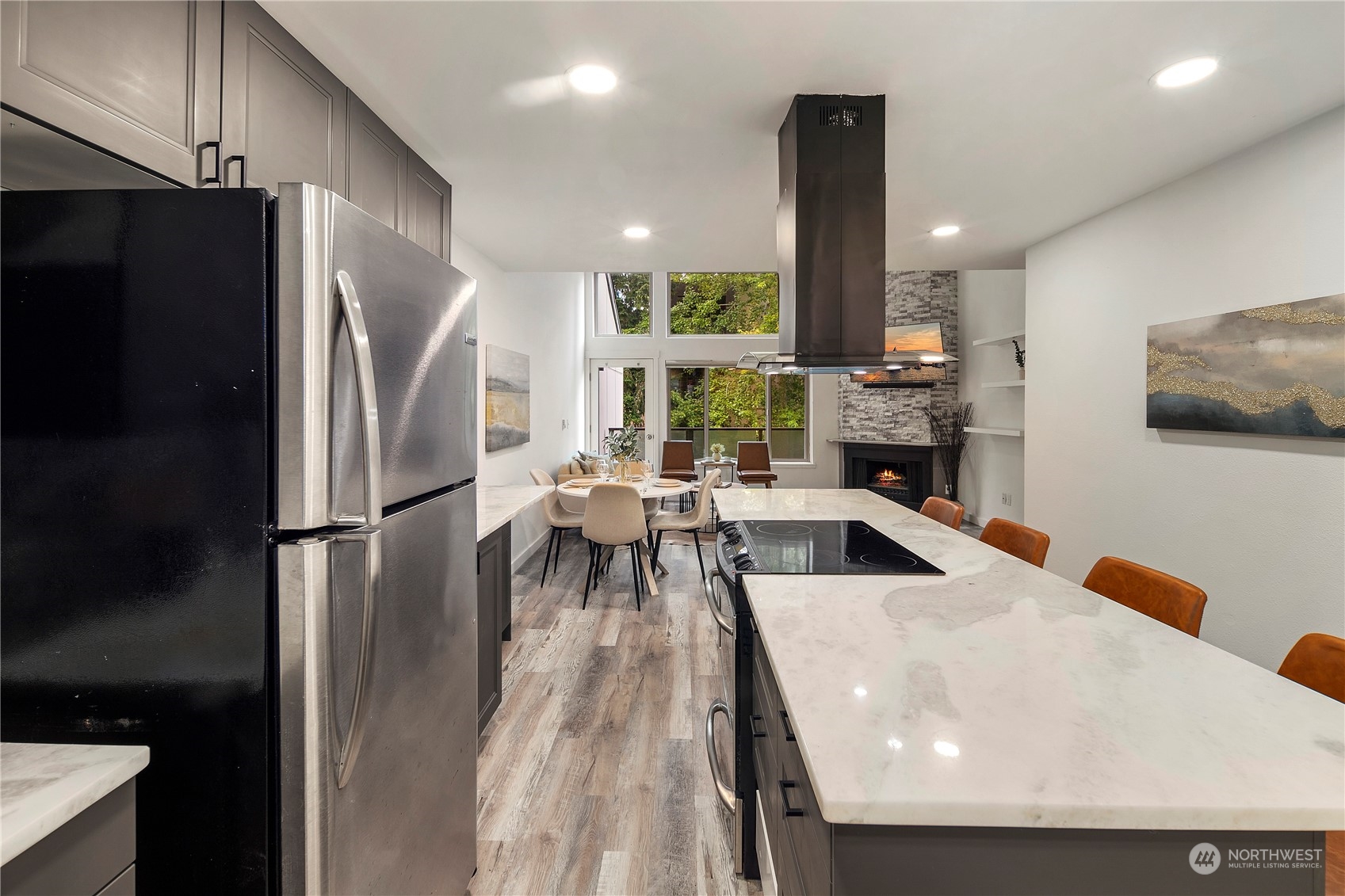 7307 Sand Point Way Northeast, Unit B618 Seattle, WA 98115 - Photo 7 of 23 a kitchen with stainless steel appliances a refrigerator a stove a sink a dining table and chairs with wooden floor