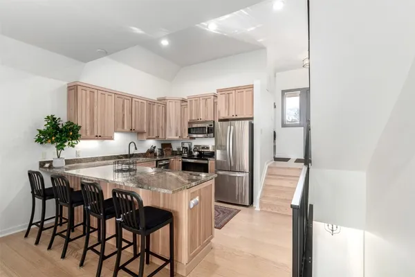 a kitchen with stainless steel appliances a table chairs refrigerator and microwave