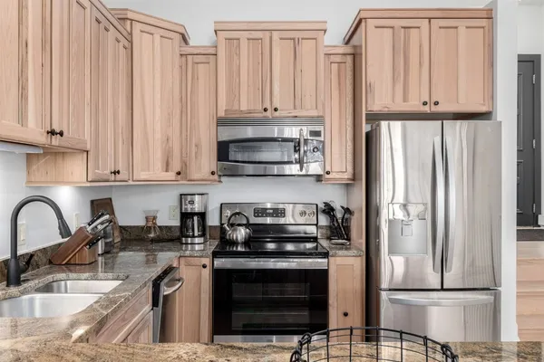 a kitchen with granite countertop a stove a sink and a refrigerator