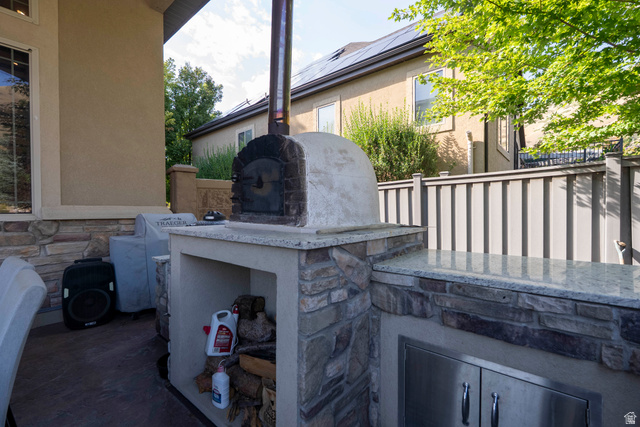 687 South 2080th Street East Springville, UT 84663 - Photo 118 of 149 Outdoor kitchen featuring a built-in pizza oven, stone veneer base, granite countertops, and stainless steel cabinetry