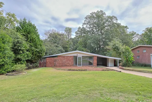 a front view of house with yard and trees in the background