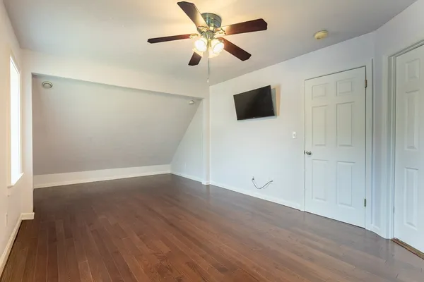 an empty room with wooden floor and a ceiling fan