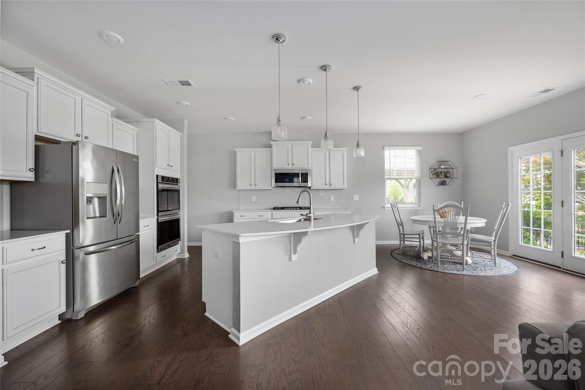 17219 Shearer Road Davidson, NC 28036 - Photo 5 of 34 a kitchen with stainless steel appliances kitchen island granite countertop a refrigerator a stove a sink a dining table and chairs with wooden floor
