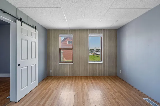 an empty room with wooden floor and windows