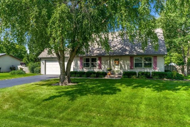 a front view of a house with a garden and trees
