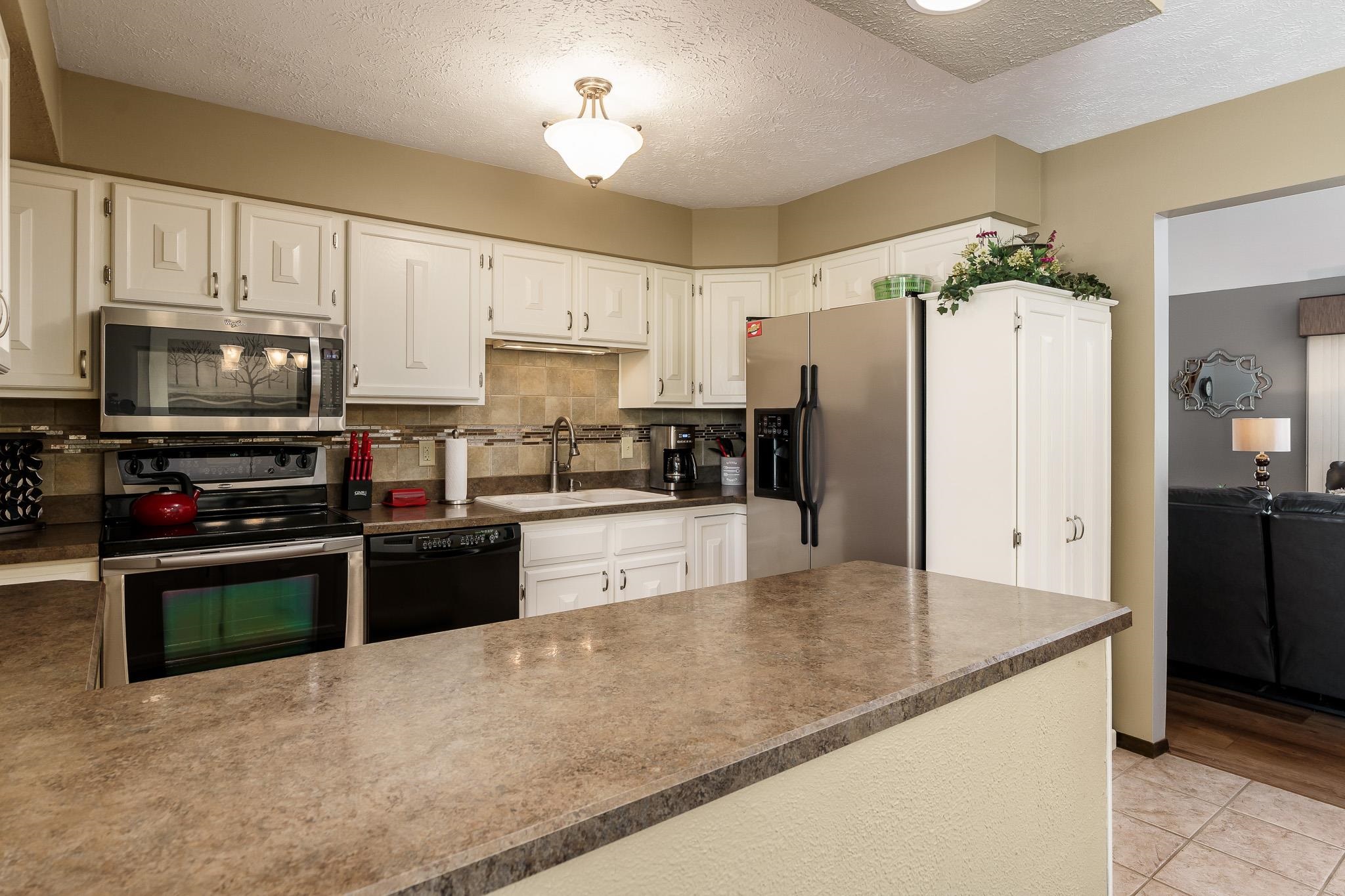 11748 Cedarbrook Road Roscoe, IL 61073 - Photo 14 of 50 a large kitchen with kitchen island granite countertop a refrigerator a stove a sink and dishwasher with wooden floor