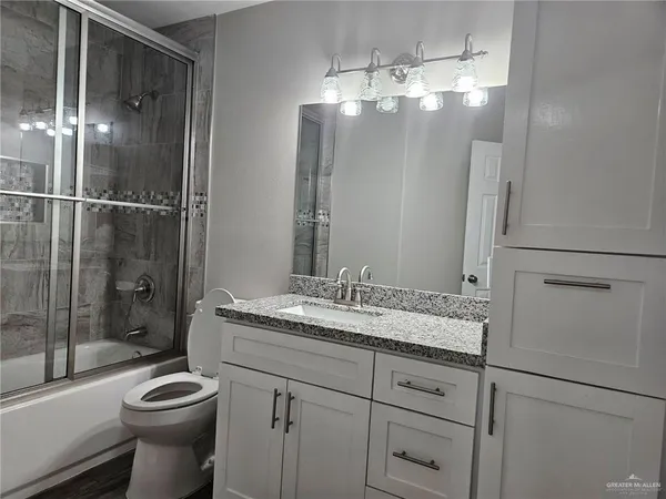 a bathroom with a granite countertop sink toilet a mirror and shower