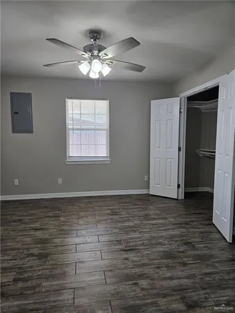 a view of an empty room with wooden floor and a window