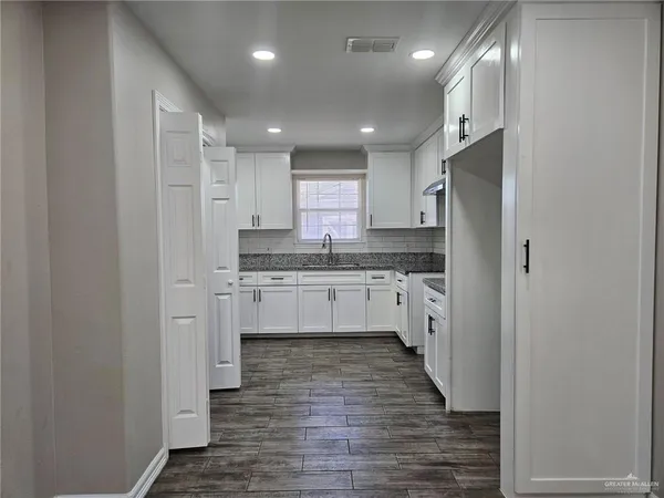 a kitchen with white cabinets and refrigerator