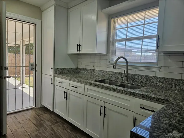 a kitchen with granite countertop white cabinets and window