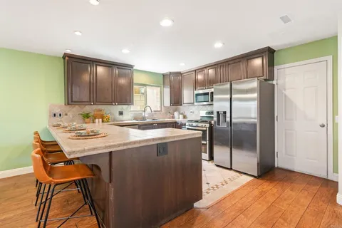 a kitchen with stainless steel appliances granite countertop a refrigerator a stove and a wooden floors