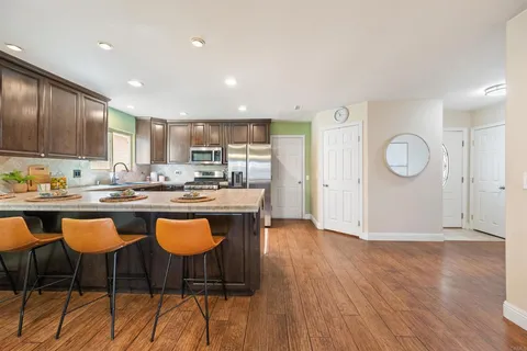 a kitchen with stainless steel appliances granite countertop a stove top oven a sink dishwasher and cabinets with wooden floor