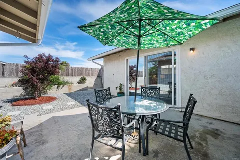 a backyard of a house with table and chairs under an umbrella