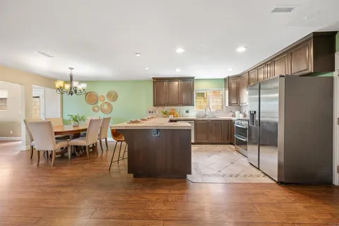 a kitchen with stainless steel appliances kitchen island granite countertop a refrigerator a stove a sink dishwasher with a dining table and chairs