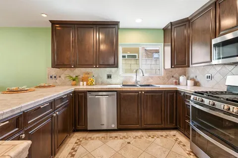 a kitchen with granite countertop wooden cabinets and stainless steel appliances