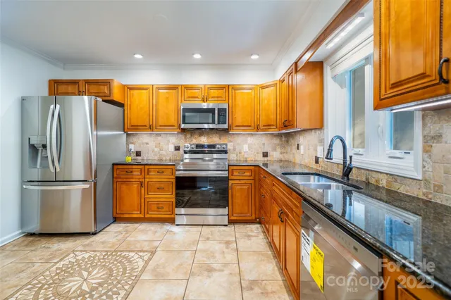 a kitchen with stainless steel appliances granite countertop a stove a sink and a refrigerator