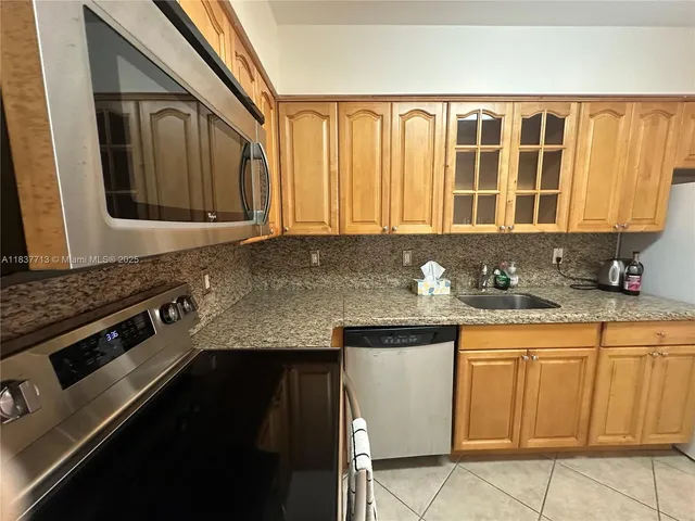 a kitchen with granite countertop a sink a stove and cabinets