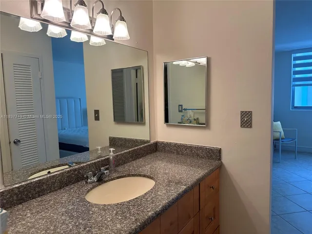 a bathroom with a granite countertop sink and a mirror