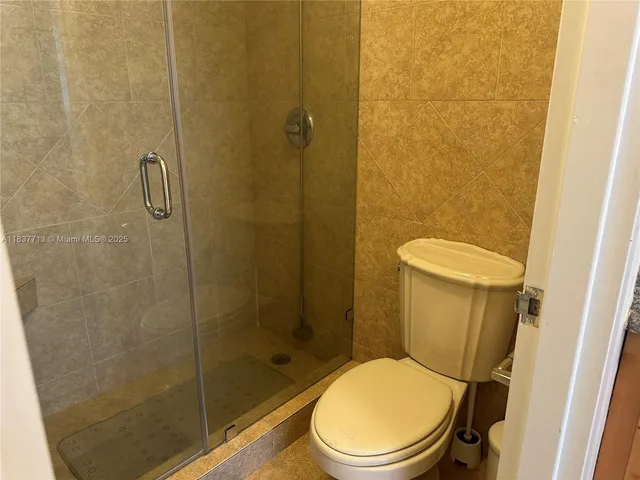 a white toilet sitting next to a shower