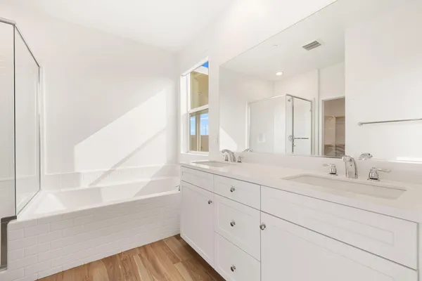 a bathroom with a double vanity sink a mirror and a bathtub