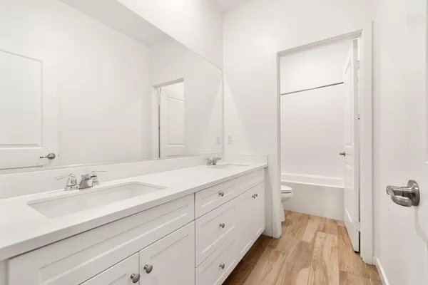 a spacious bathroom with a double vanity sink a mirror and a bathtub