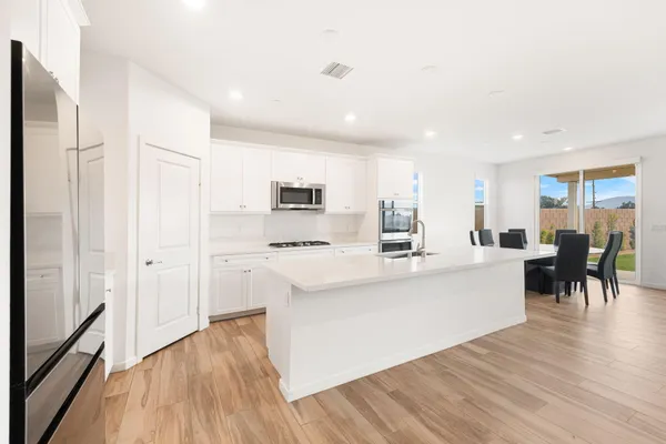 a large white kitchen with stainless steel appliances granite countertop a stove and a refrigerator