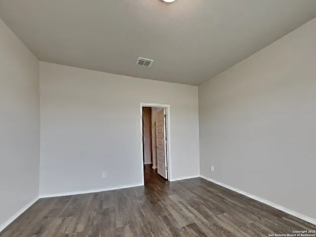 a view of an empty room with wooden floor and closet