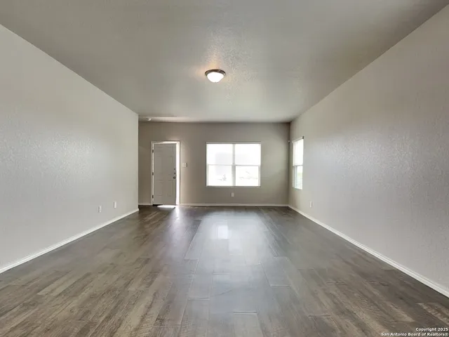 a view of an empty room with wooden floor and window