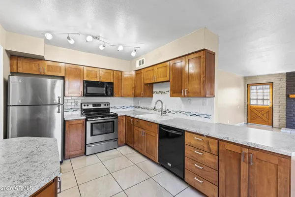 a kitchen with stainless steel appliances granite countertop a refrigerator a stove top oven and sink