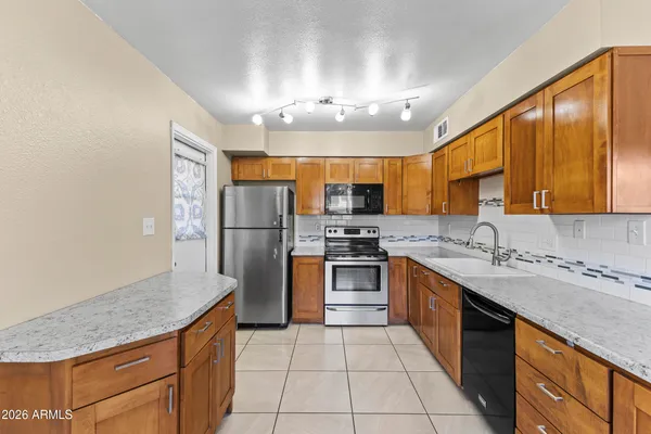 a large kitchen with stainless steel appliances granite countertop a sink stove and refrigerator