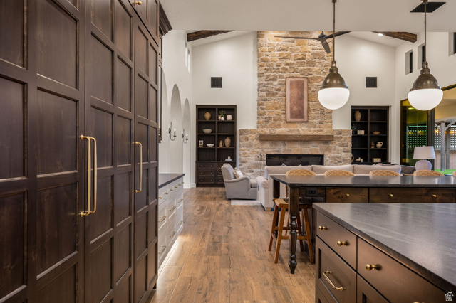 4871 South Homestead Way Washington, UT 84780 - Photo 149 of 151 Kitchen featuring dark wood finish cabinetry, light wood finished floors, a stone fireplace, open floor plan, and pendant lighting