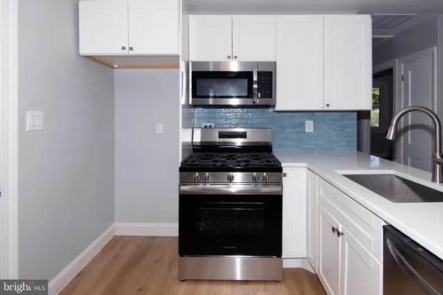 a kitchen with granite countertop white cabinets and stainless steel appliances