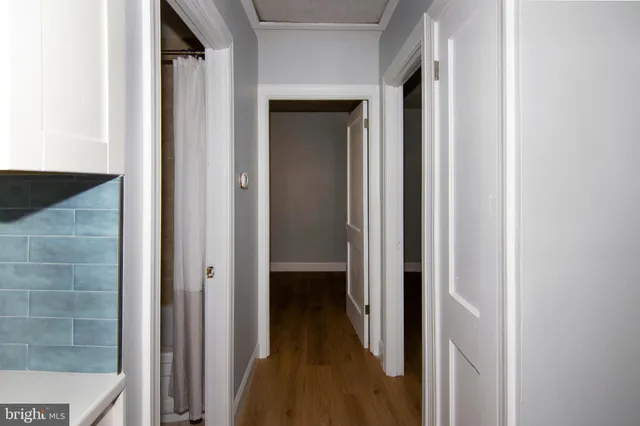 a view of a hallway with wooden floor and a bathroom