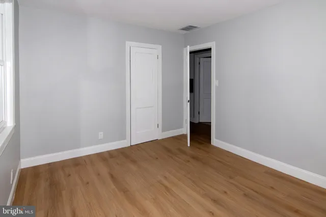 a view of an empty room with wooden floor and closet