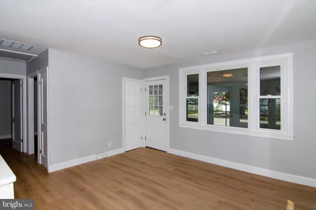 an empty room with wooden floor and windows