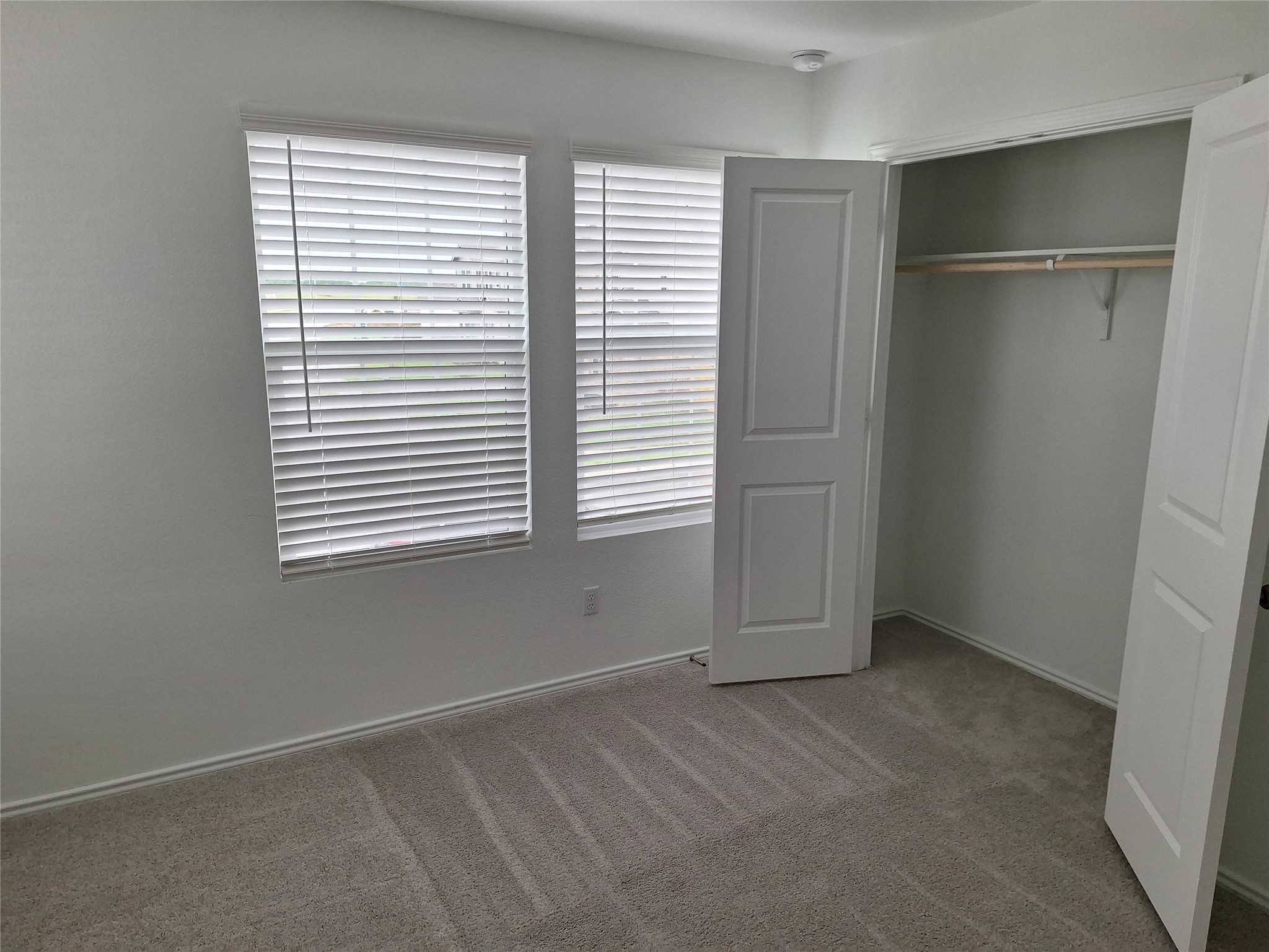 18001 Prairie Falcon Way Pflugerville, TX 78660 - Photo 35 of 38 Neutral-toned carpeting complements the white walls and trim, accented by two windows with horizontal blinds