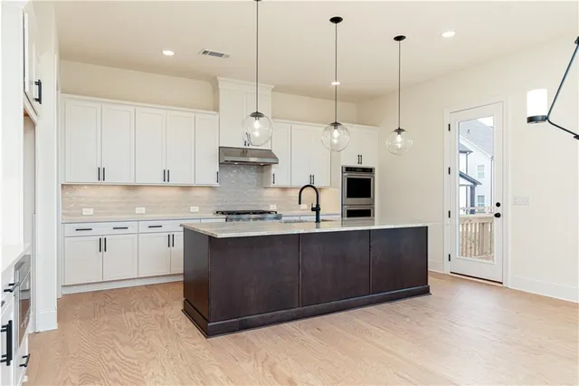 a large kitchen with stainless steel appliances granite countertop a stove a sink and a refrigerator