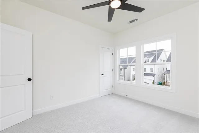 an empty room with windows and fan