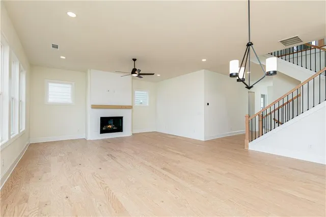 a view of a livingroom with a fireplace a chandelier fan and wooden floor