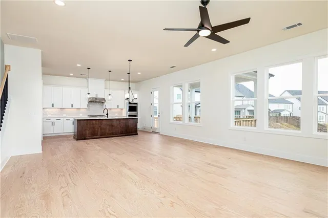 a large white kitchen with kitchen island a large window appliances and cabinets