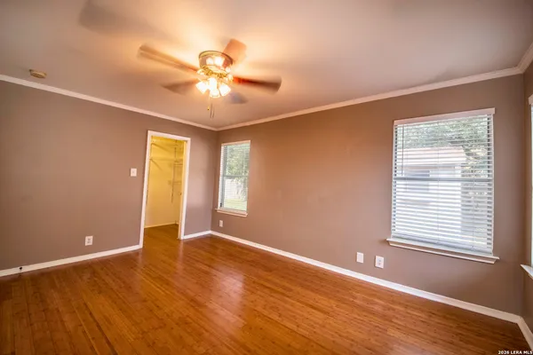 a view of an empty room with wooden floor and a window