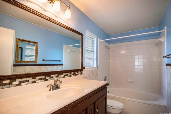 a bathroom with a sink a toilet a mirror and shower