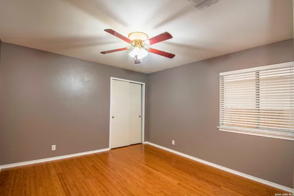 a view of an empty room with window and a chandelier fan