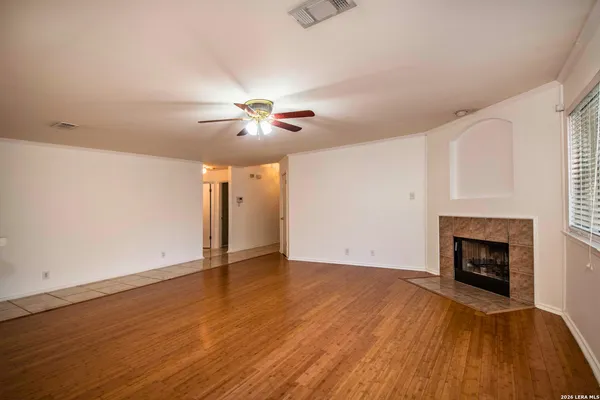 an empty room with wooden floor fireplace and a window