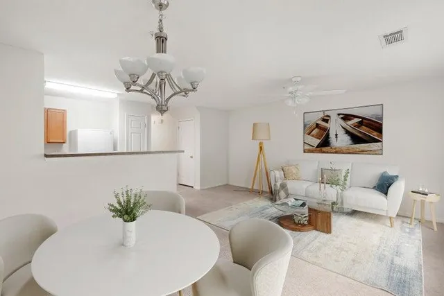 a living room with furniture flowers and a mirror